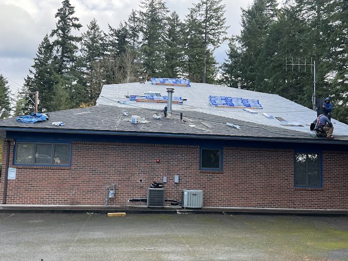 A man is working on the roof of a brick house.