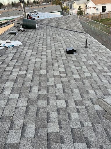 A cat is laying on the roof of a house.