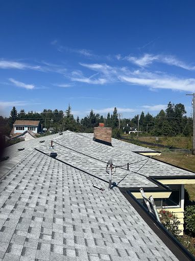 A roof with a chimney on it and a blue sky in the background.