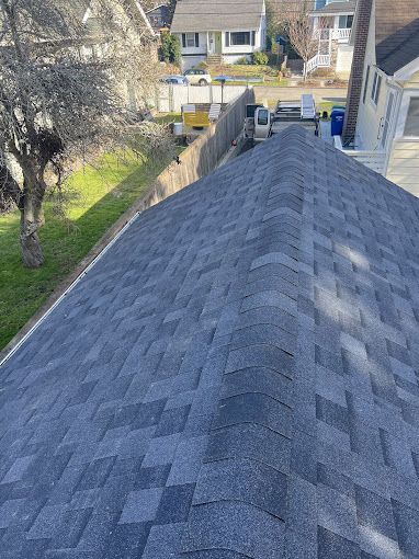 A roof with a lot of shingles on it and a fence in the background.