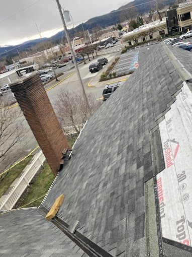 A roof with shingles being installed and a chimney.