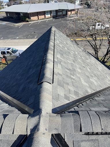 The roof of a building with a pyramid shaped roof and a parking lot in the background.