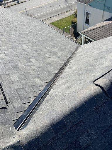 A close up of a roof with shingles and a metal gutter.