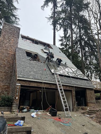 A group of people are working on the roof of a house.