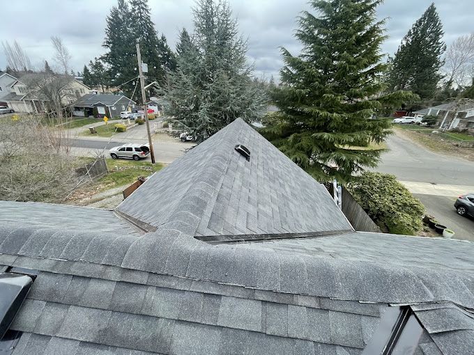 A roof with a pyramid shaped roof and trees in the background