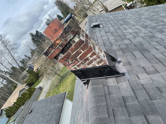 A brick chimney is sitting on top of a roof.