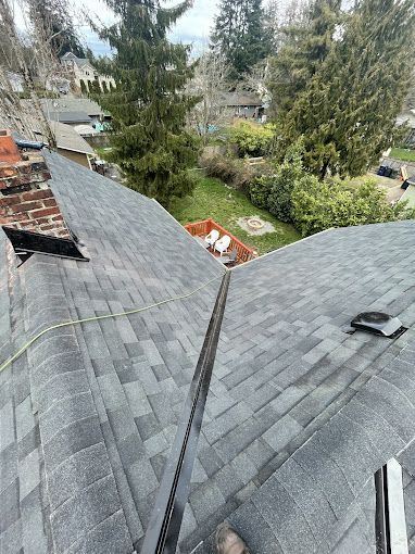A roof with a lot of shingles on it and trees in the background.