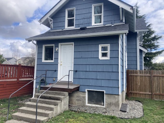 A blue house with stairs leading up to the front door