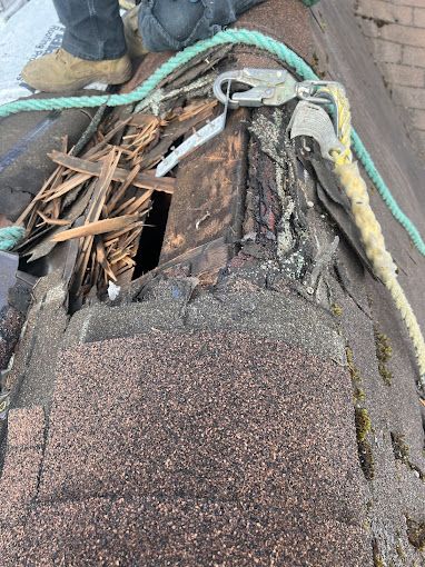 A person is working on a roof with a rope and safety harness.