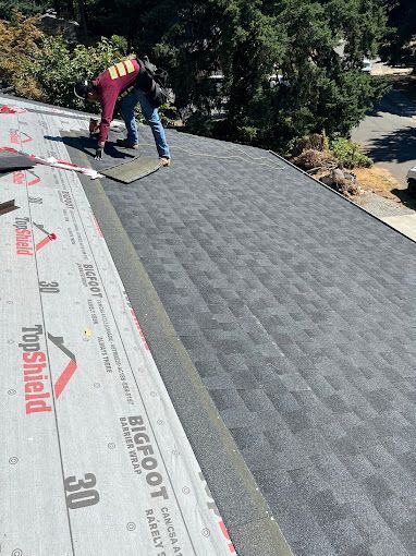 A man is laying shingles on a roof.