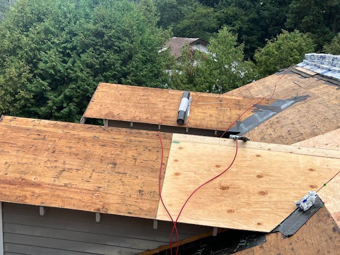 The roof of a house is being repaired with plywood.