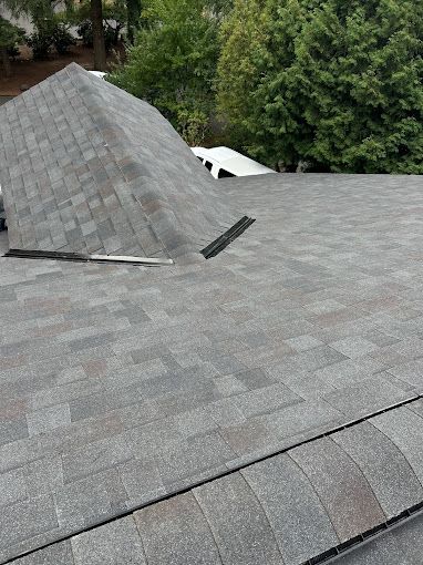 A roof with a lot of shingles on it and trees in the background.