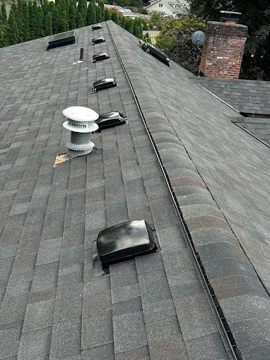 A roof with a lot of vents on it and a chimney.