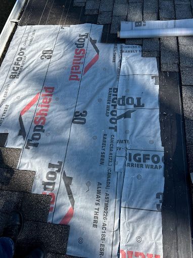 A roll of topshield roof wrap is laying on a brick roof.