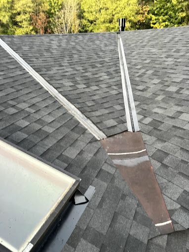 A roof with a skylight and a chimney on it.
