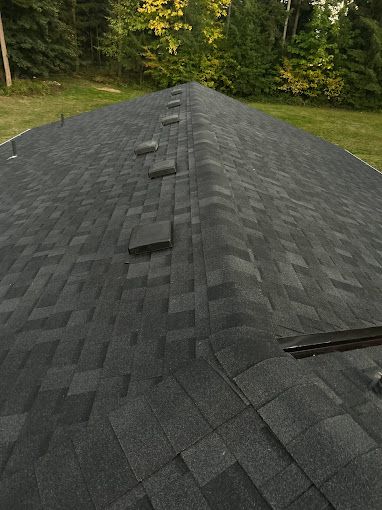 A roof with a lot of shingles on it and trees in the background.