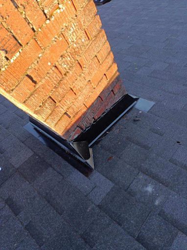A brick chimney is sitting on top of a roof.