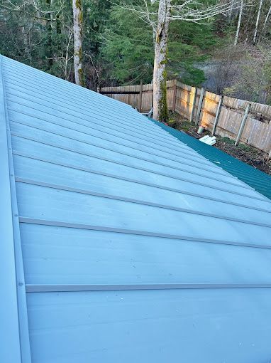 A close up of a metal roof with a green fence in the background.