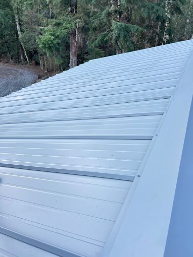 A close up of a metal roof with trees in the background.