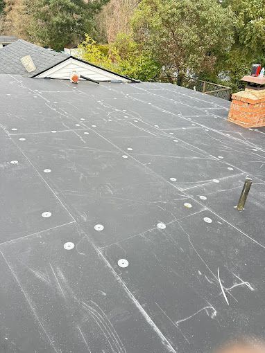 A black roof with white dots on it is being installed on a house.