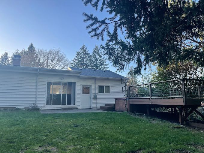 A white house with a wooden deck in the backyard.
