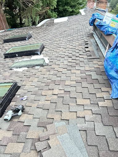 A roof with shingles missing and skylights on it.