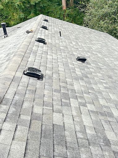 A roof with a lot of shingles and vents on it.