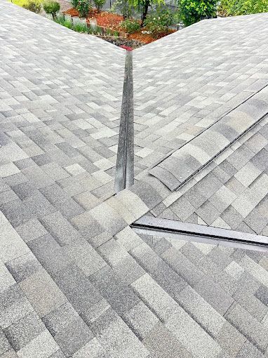 A close up of a roof with shingles and a chimney.