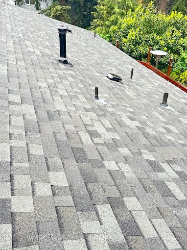 A close up of a roof with shingles and a chimney.