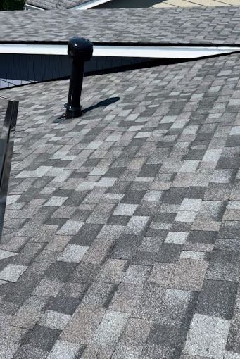 A close up of a roof with shingles and a chimney on it.