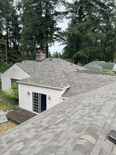An aerial view of a roof of a house with trees in the background.