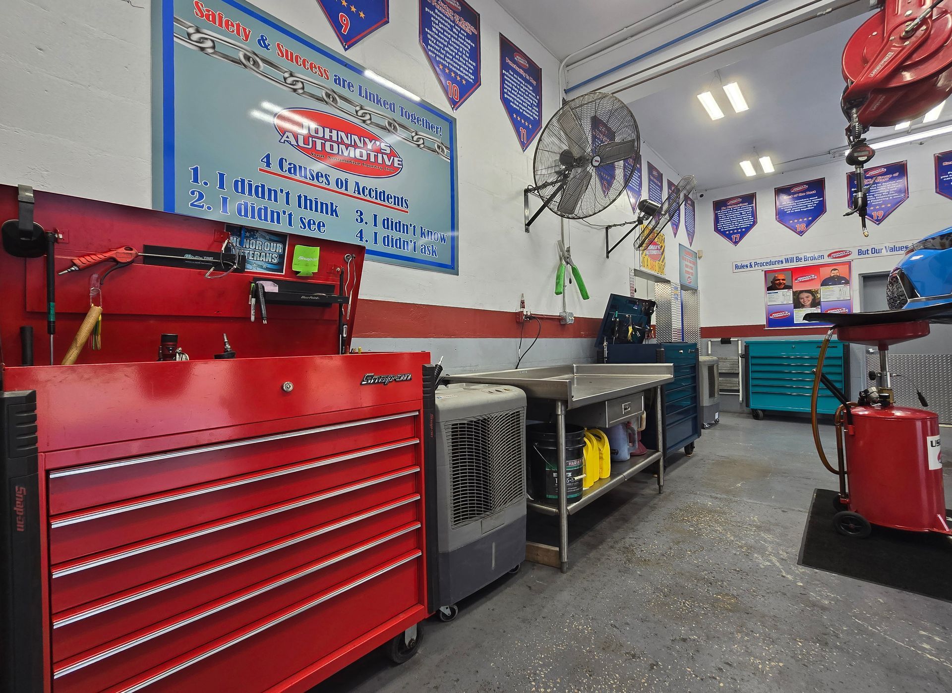 Red tool chest in a well-lit auto repair shop with tools and banners. | Johnny's Automotive
