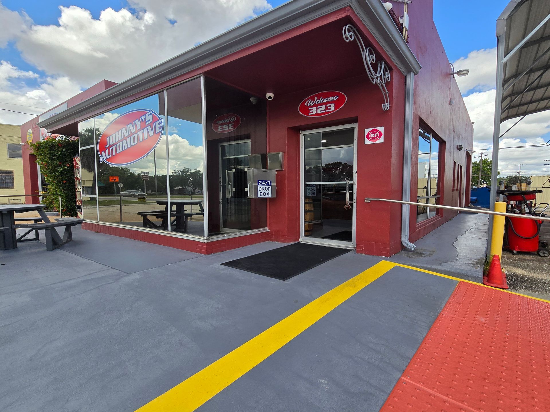 Exterior of Johnny's Car Care, a red building with large windows and an entrance, a sunny day. | Johnny's Automotive