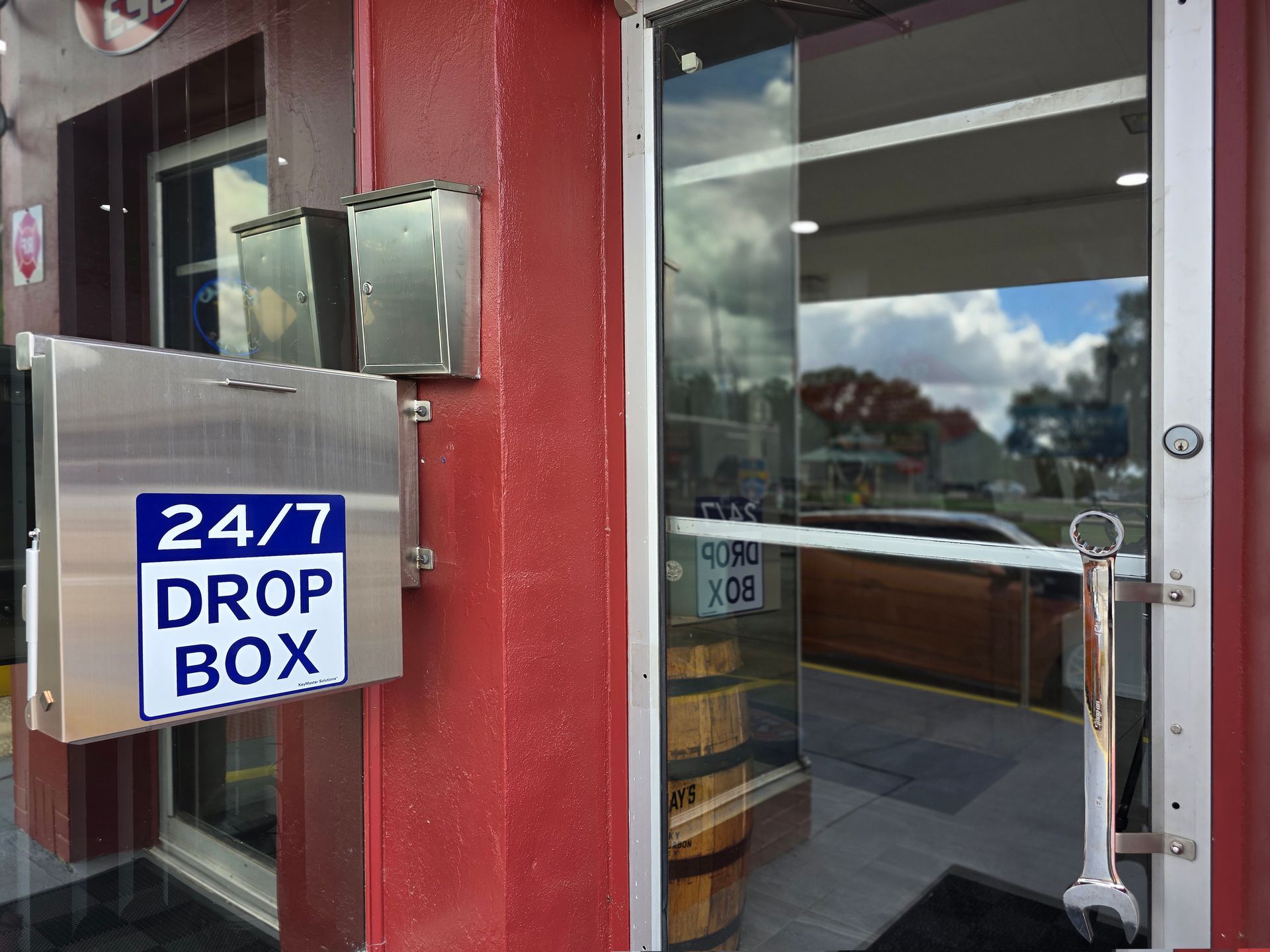 Exterior of building with 24/7 drop box, glass door, red walls, and a view of the street. | Johnny's Automotive