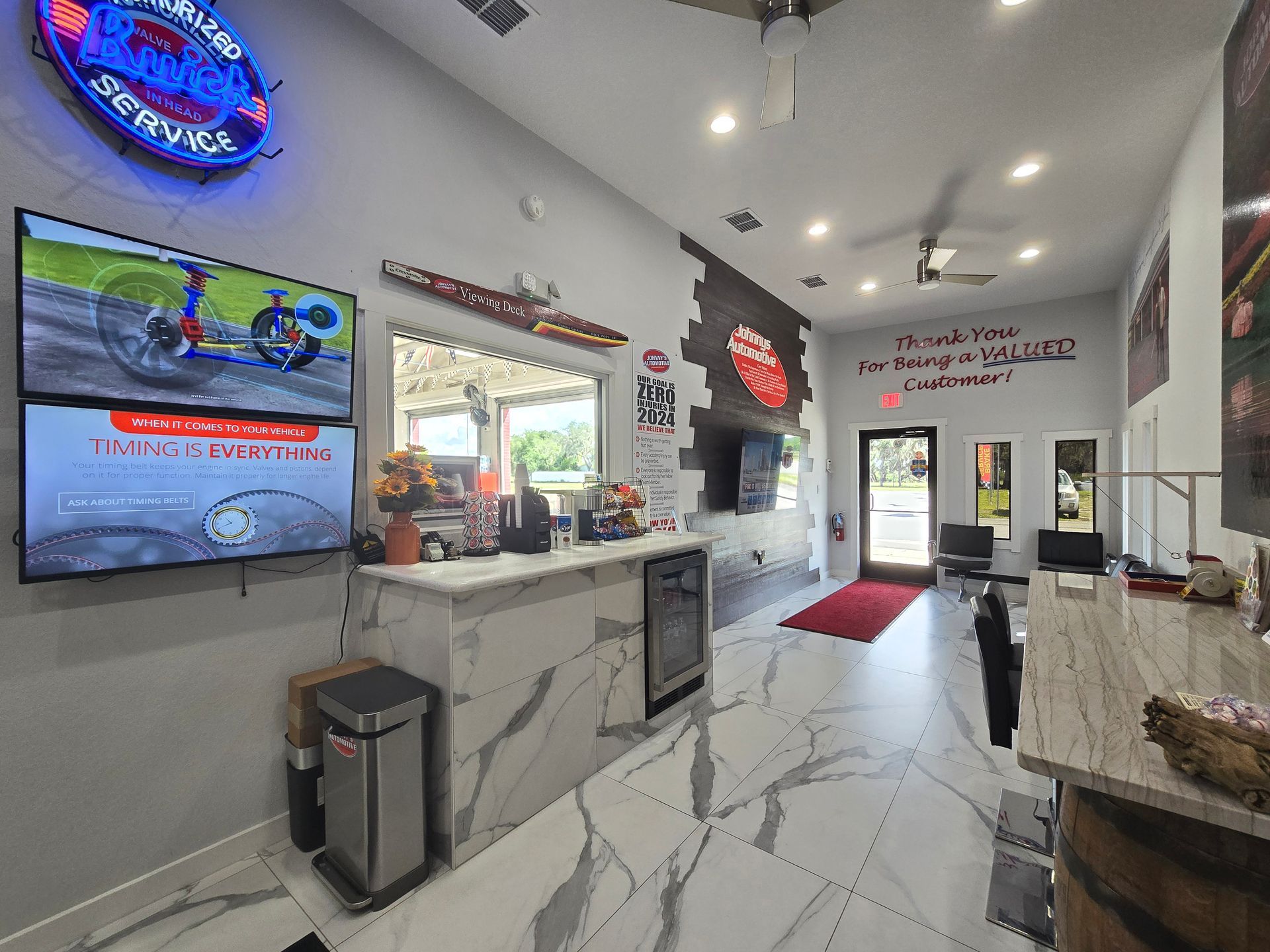 Auto repair shop interior with reception desk, TVs, and waiting area. | Johnny's Automotive