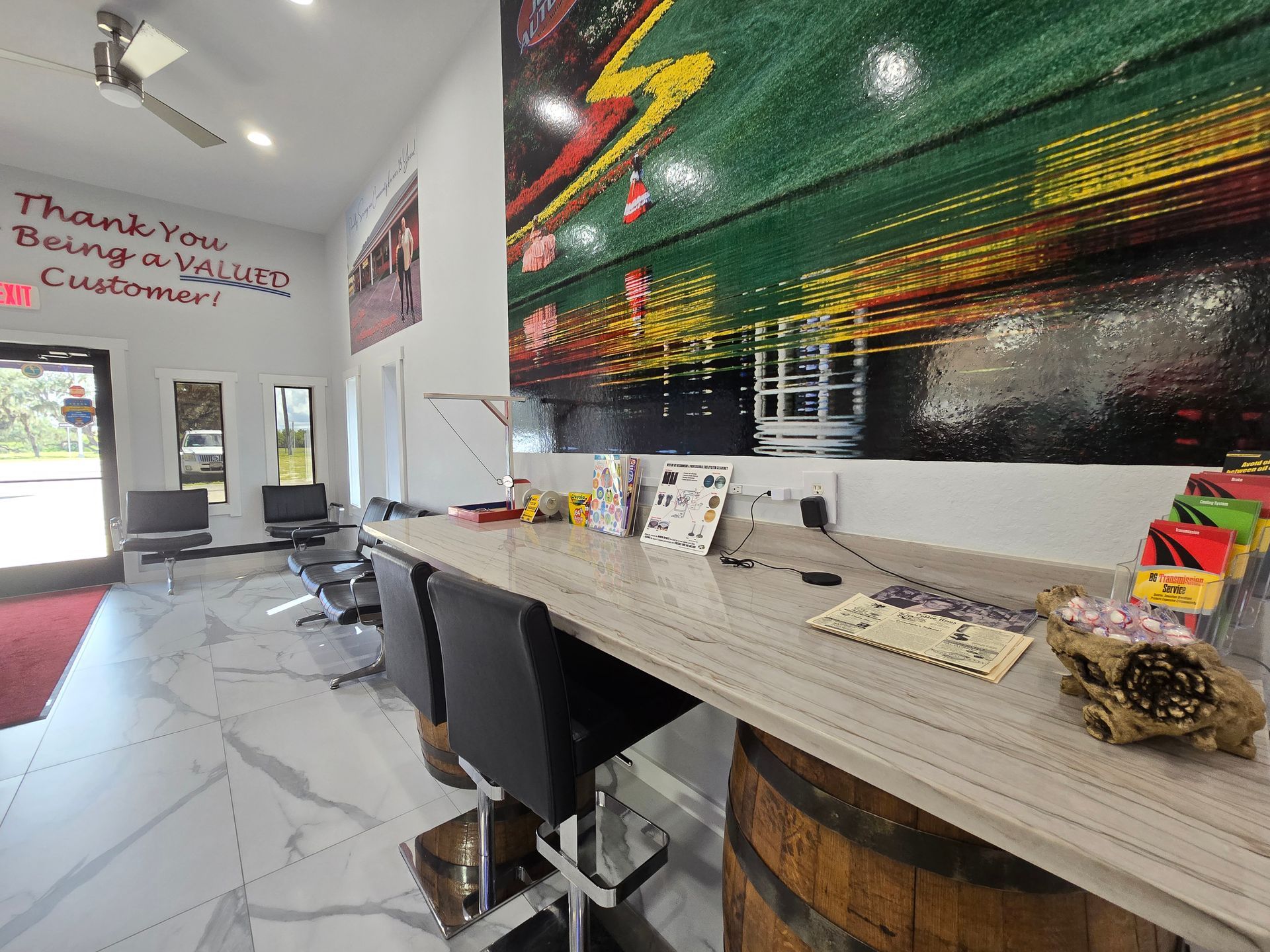 Reception area with bar-height counter, stools, and a large colorful artwork. | Johnny's Automotive