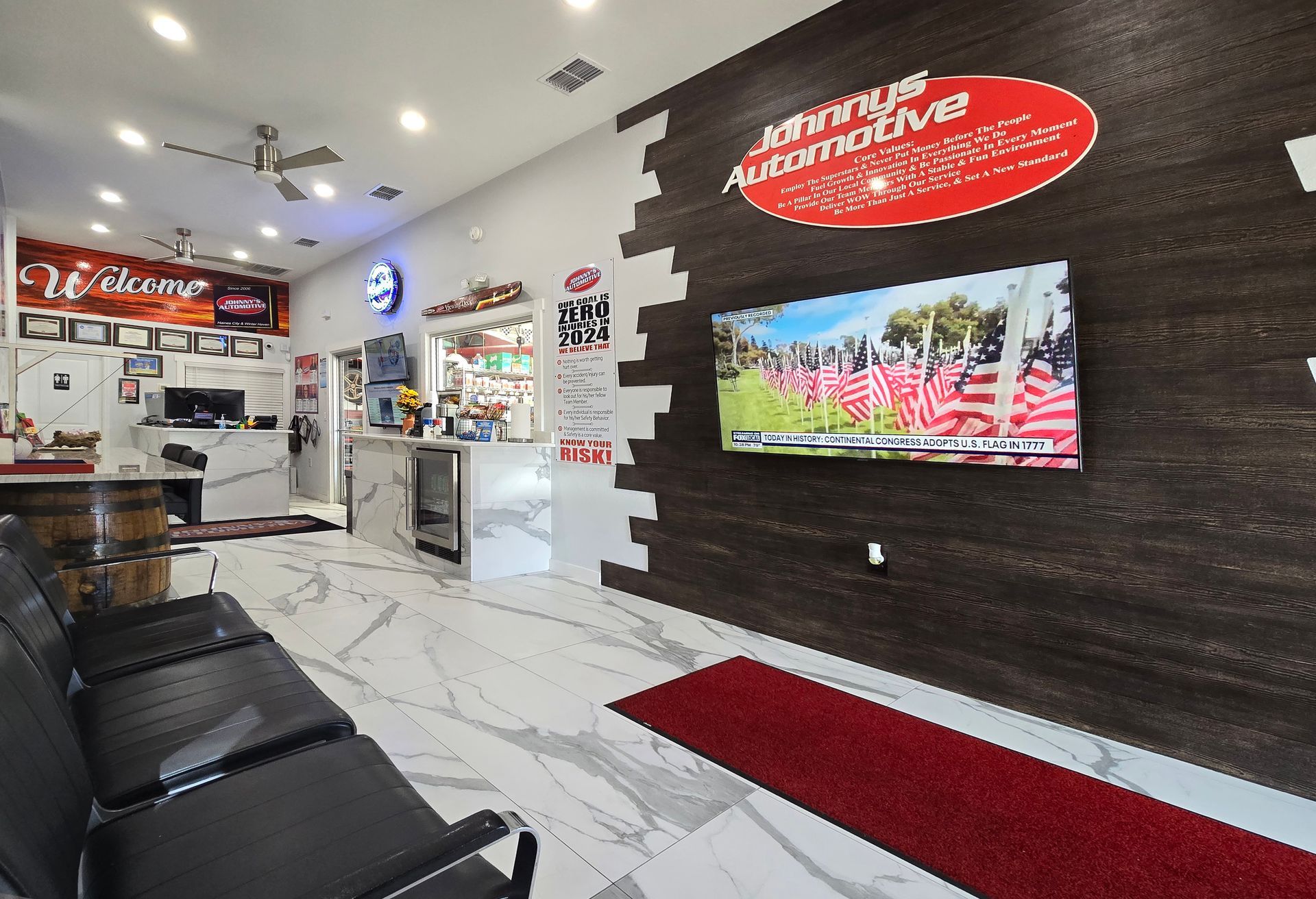 Interior of an auto shop waiting area with seating, TV, and a welcome sign. | Johnny's Automotive