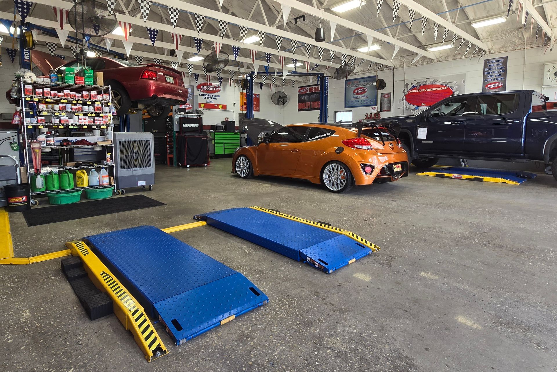 An auto repair shop with cars on lifts, a ramp, and shelves with supplies. | Johnny's Automotive