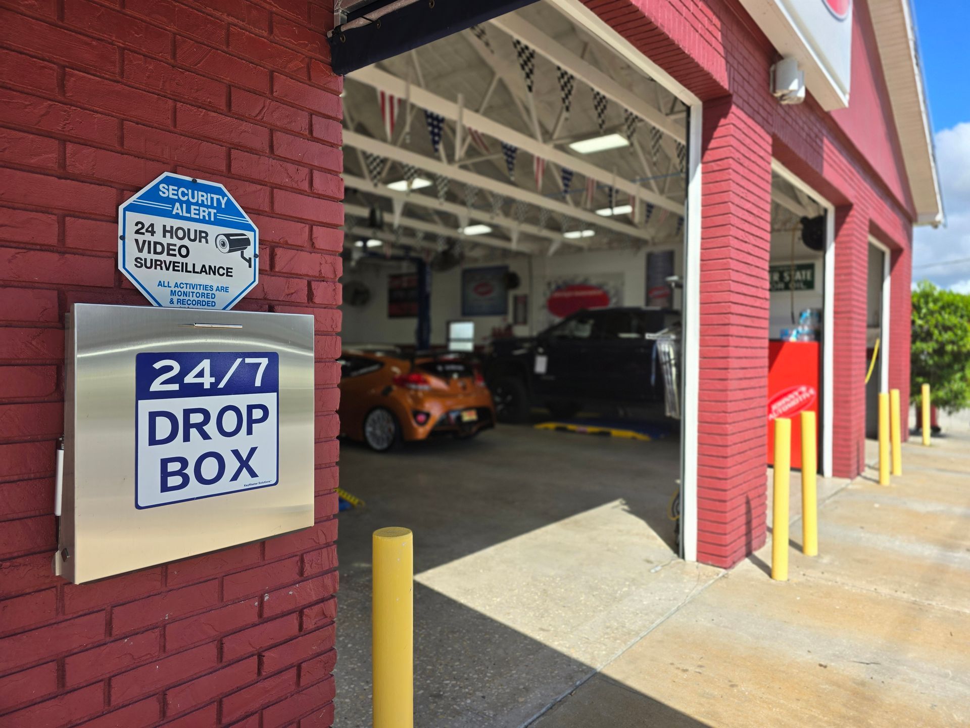 Exterior of a car repair shop with a drop box and open garage bays. Red brick building, cars inside. | Johnny's Automotive