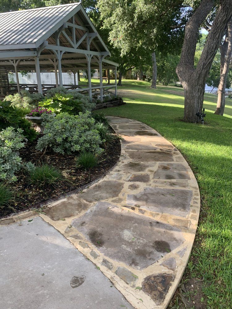 A stone walkway leading to a gazebo in a park.