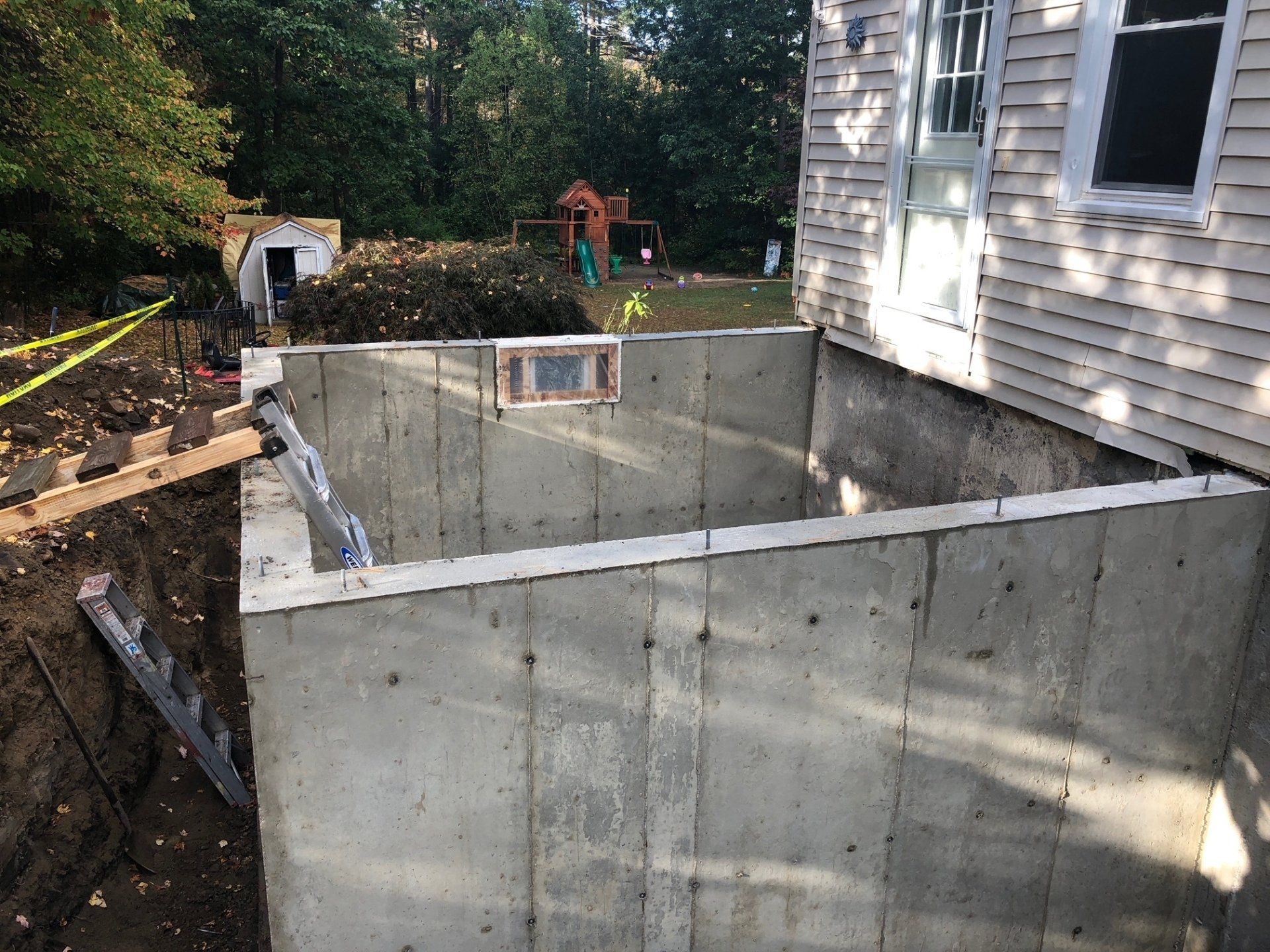 A concrete wall is being built in front of a house.