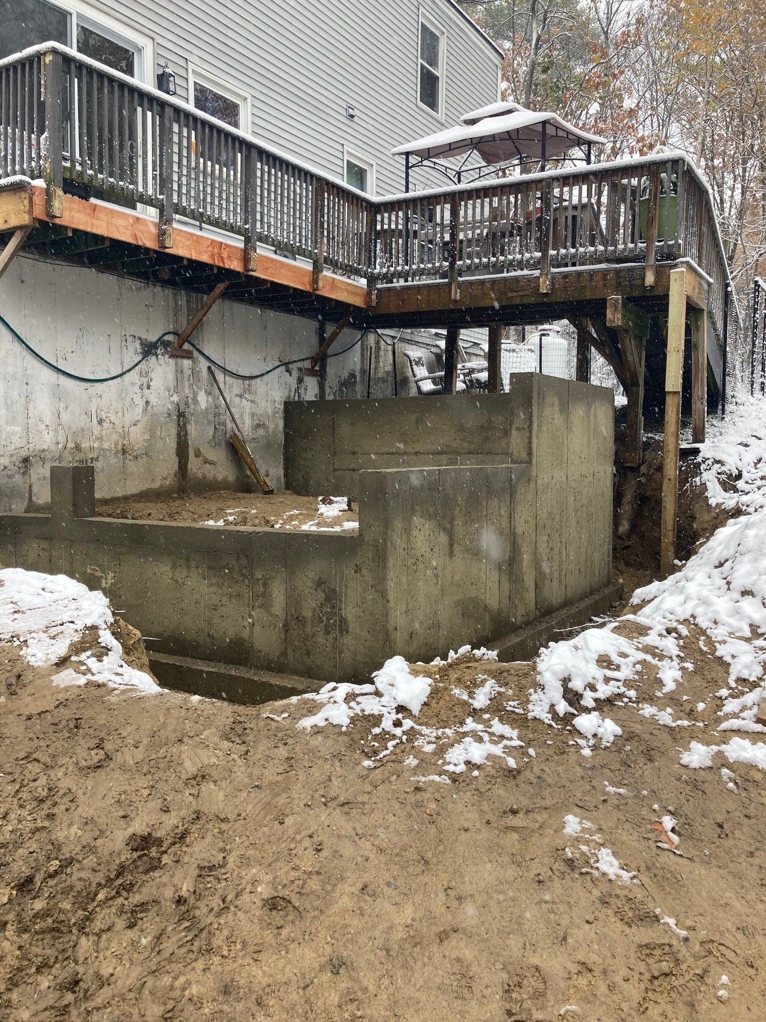 A house with a wooden deck over a concrete foundation.