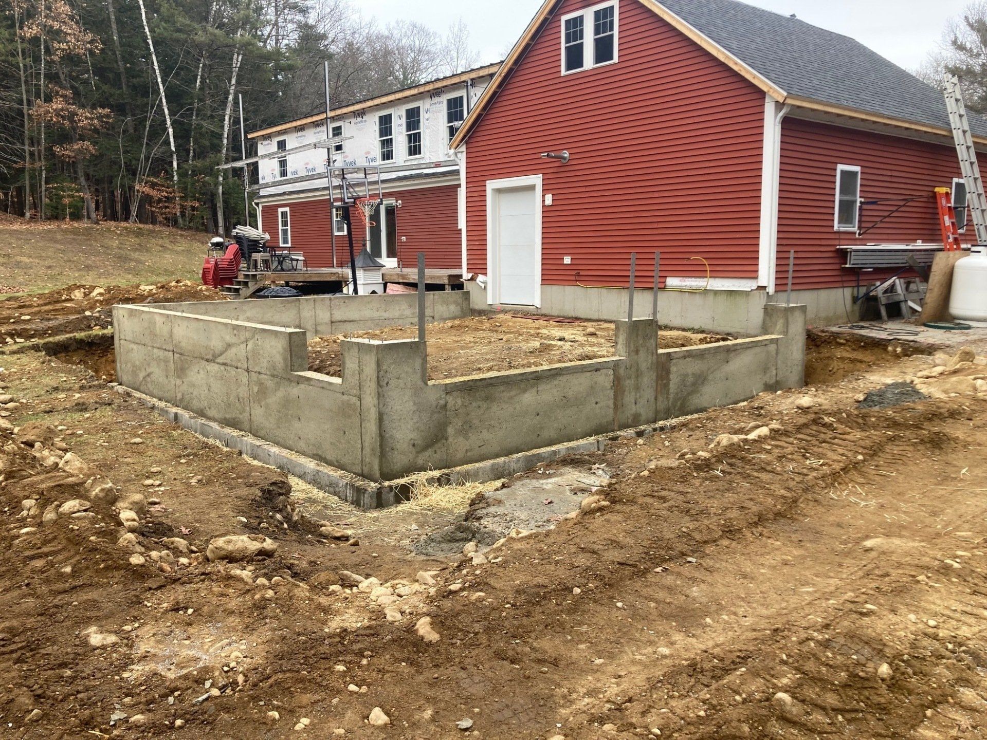 A red house is being built in the middle of a dirt field.