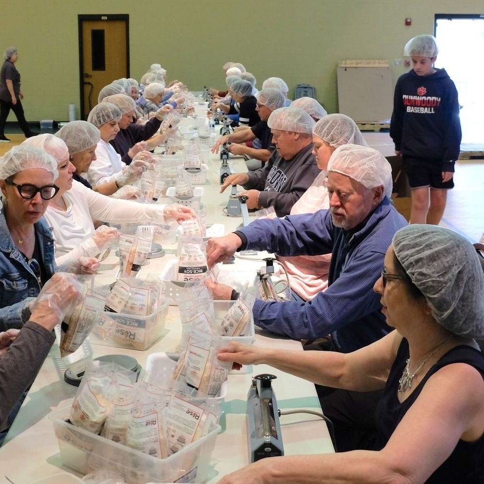People in hairnets assemble meal packets for Rise Against Hunger