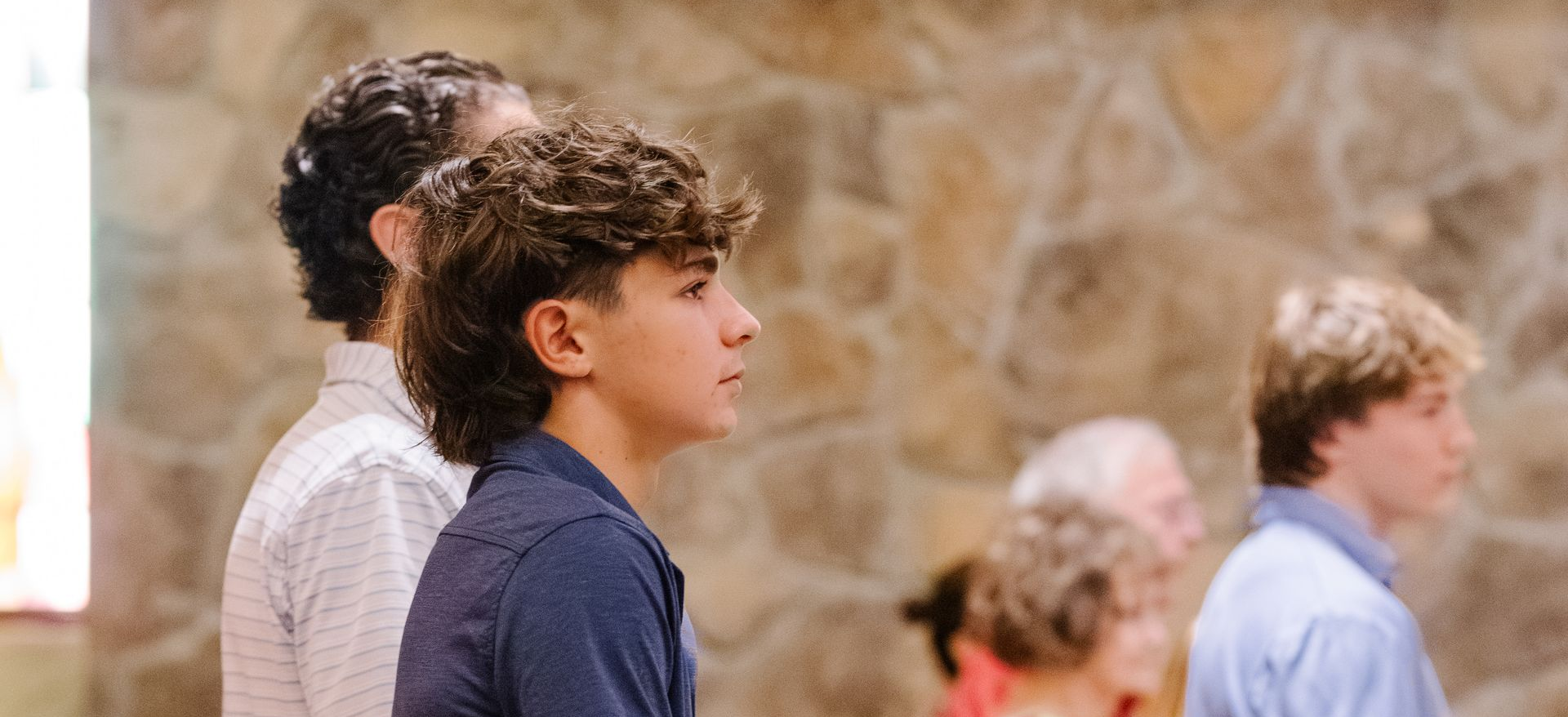 People standing in a room with stone walls, looking towards the right.