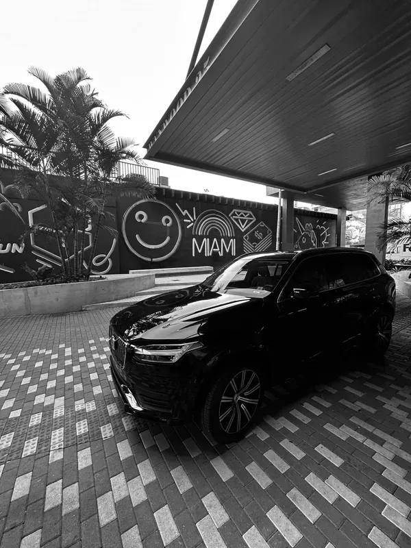 A black and white photo of a car parked under a canopy.