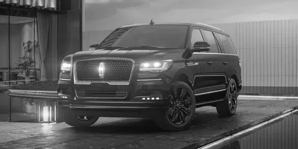 A black and white photo of a lincoln navigator parked in front of a building.