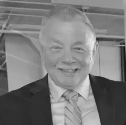 A man in a suit and tie is smiling in a black and white photo.