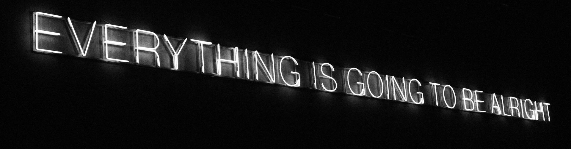 Glowing neon sign on a black background, spelling 