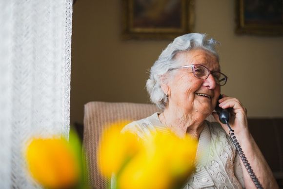 Un'anziana signora portatrice di soluzioni digitali per l'udito che telefona a un'amica